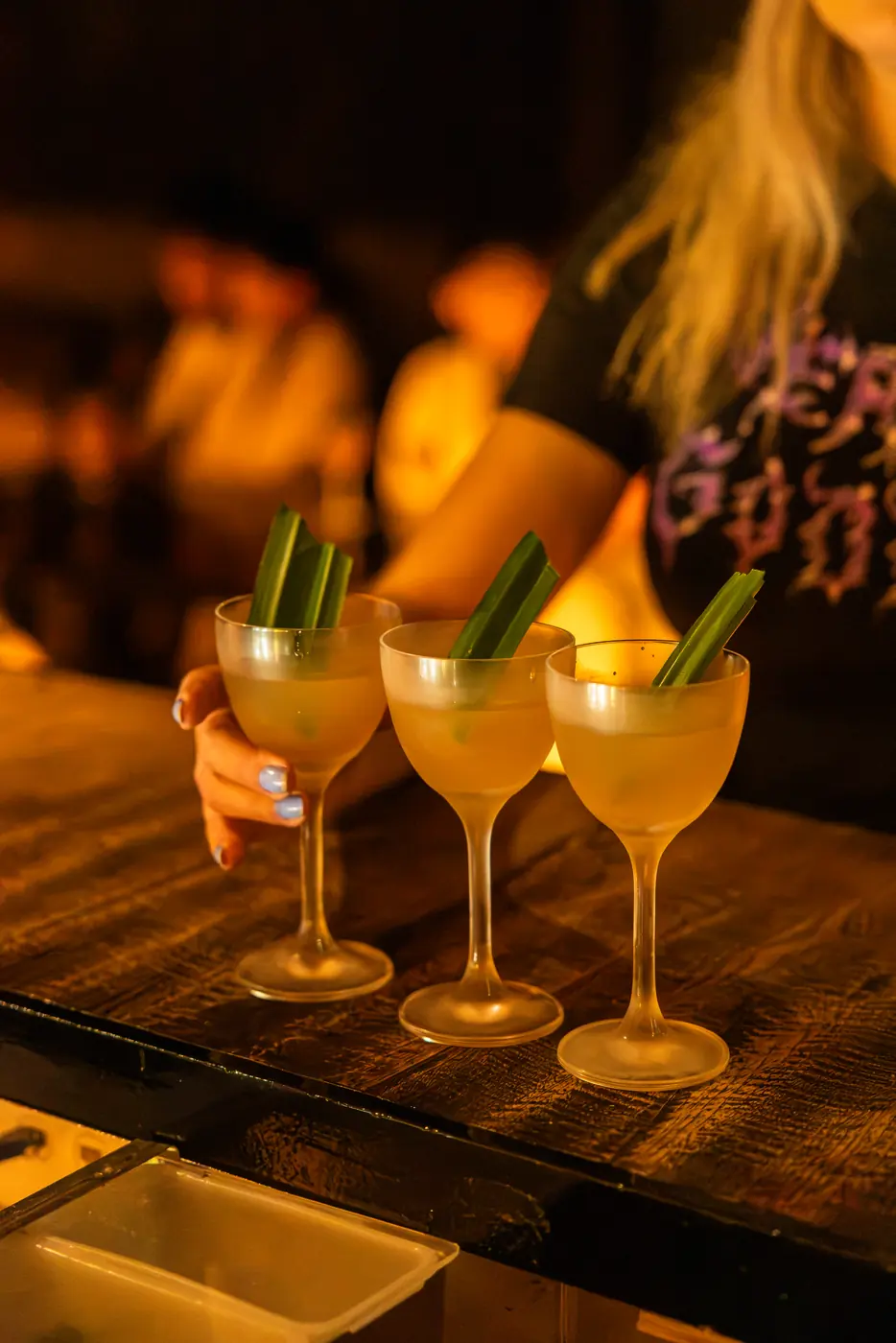 Three pale cocktails garnished with cucumber on the bar