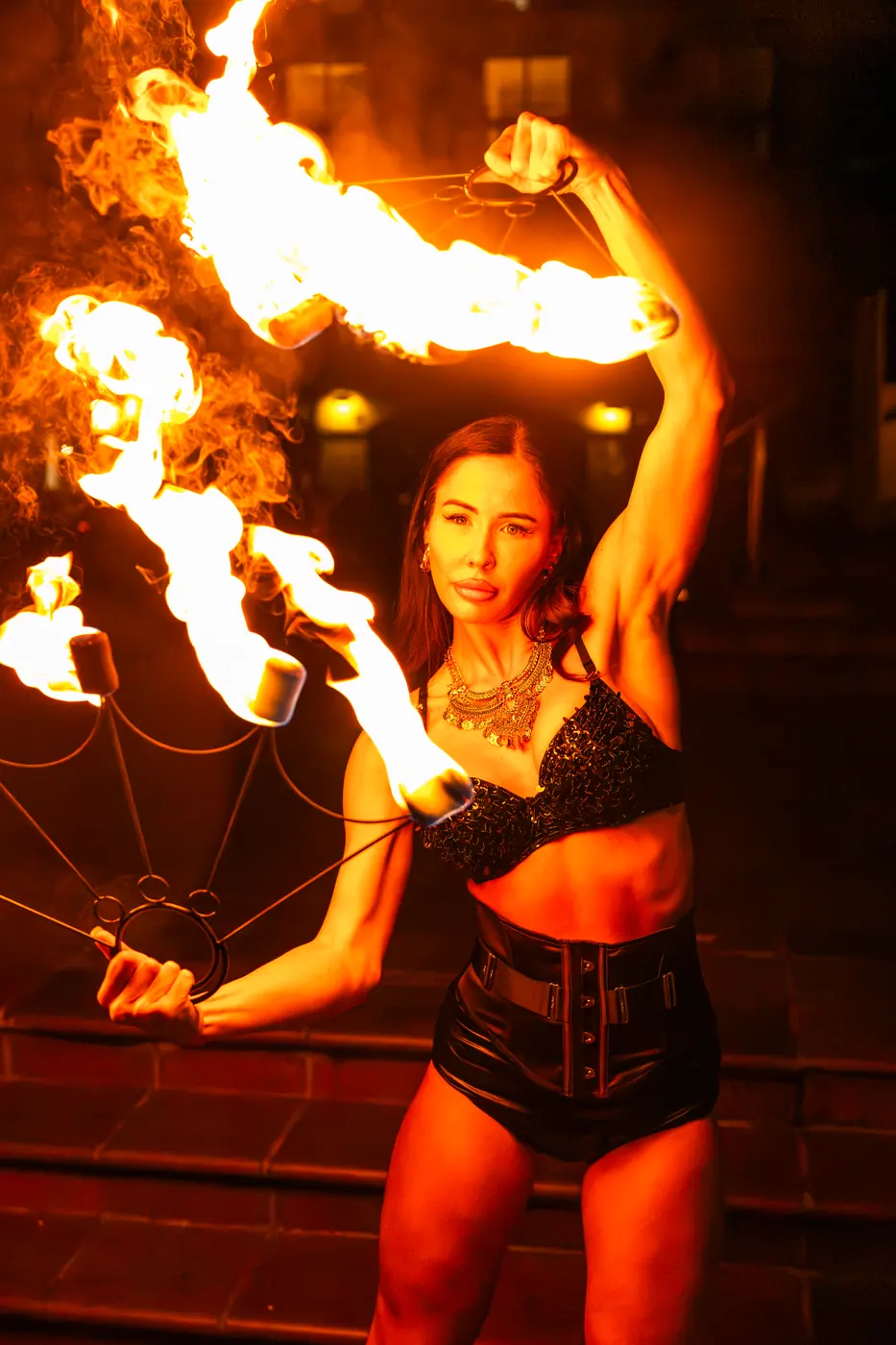 A fire performer with flaming fans outside Soi Fire
