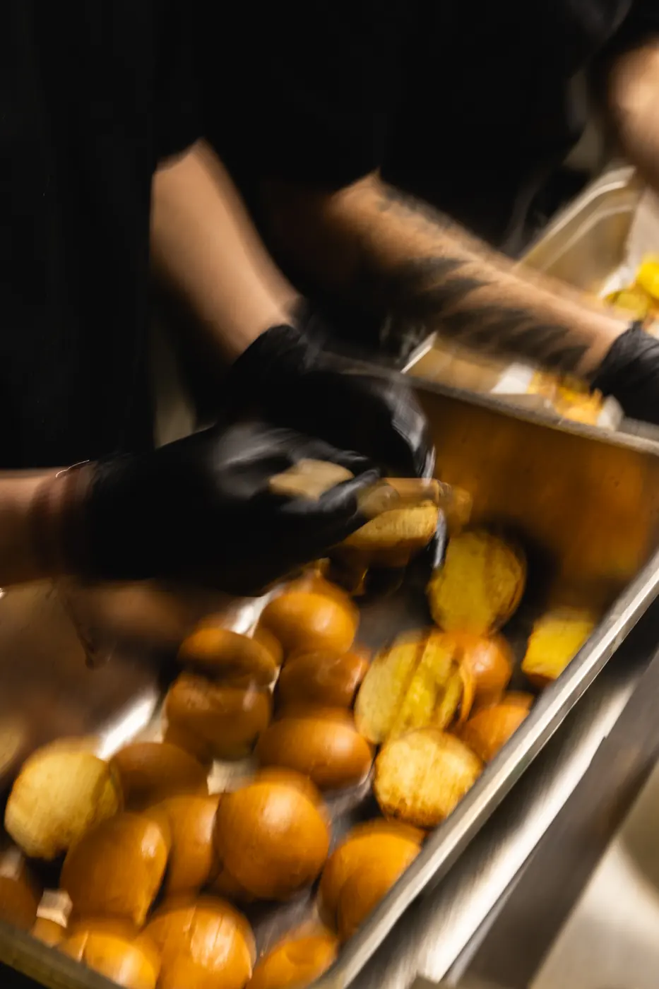 Gloved hands plating food at the kitchen pass