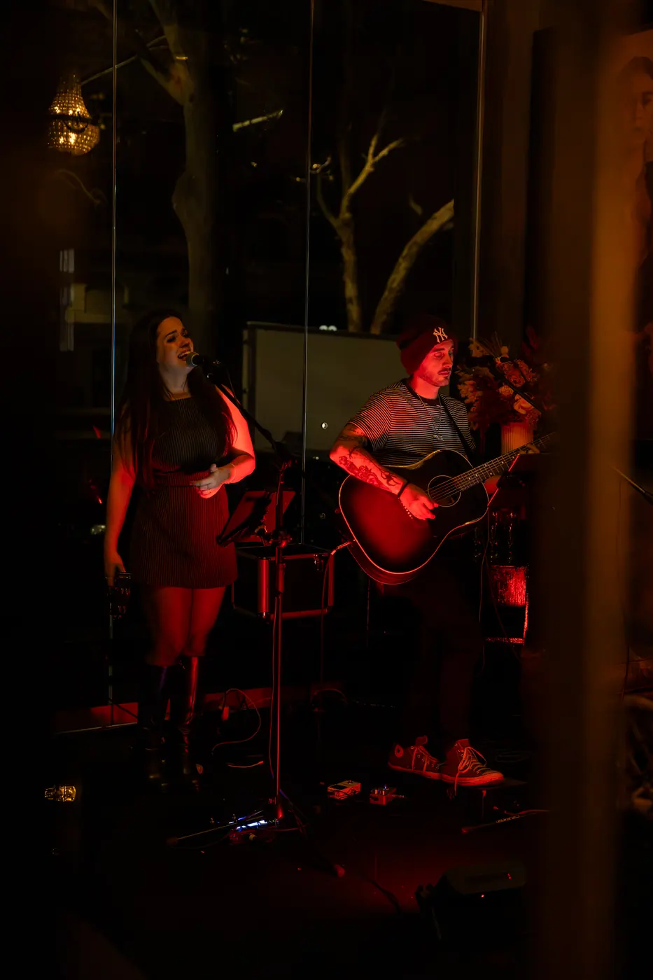 A duo playing live music under red light at Soi Fire