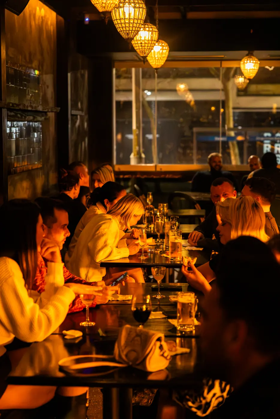 A long table of guests under the lanterns at Soi Fire